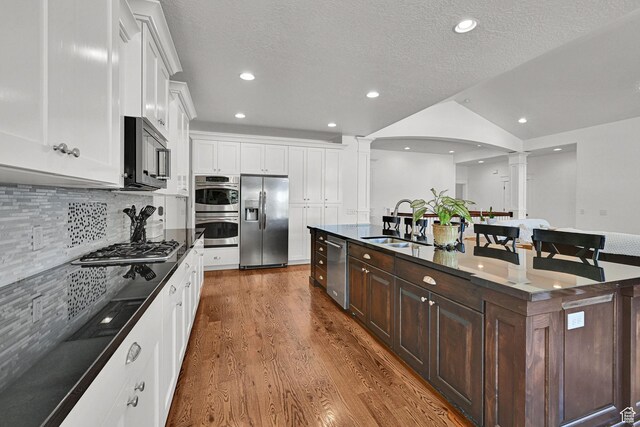514 Rigby Rd, Farmington, UT 84025 - kitchen with decorative columns, appliances with stainless steel finishes, wood finished floors, dark brown cabinetry, and white cabinets
