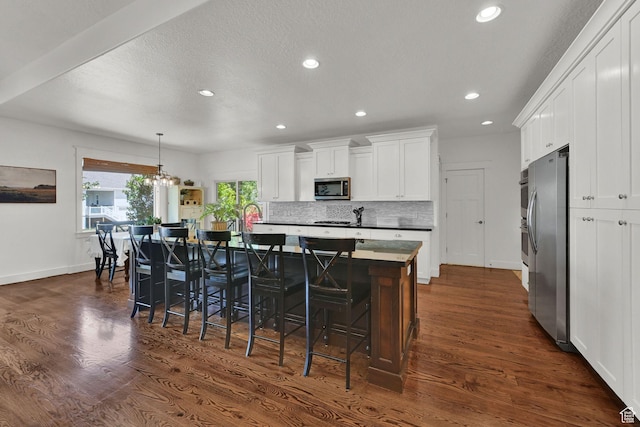 514 Rigby Rd, Farmington, UT 84025 - kitchen with appliances with stainless steel finishes, dark wood-style flooring, white cabinets, a kitchen island with sink, and recessed lighting