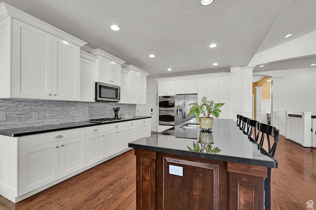 514 Rigby Rd, Farmington, UT 84025 - kitchen with ornate columns, appliances with stainless steel finishes, dark countertops, dark wood finished floors, and recessed lighting
