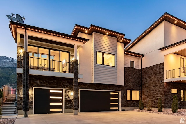 1621 E Box Elder Cir, Alpine, UT 84004 - contemporary house with stone siding, a balcony, a garage, concrete driveway, and a mountain view
