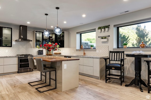 1621 E Box Elder Cir, Alpine, UT 84004 - kitchen with range with two ovens, wall chimney range hood, white cabinets, modern cabinets, and a breakfast bar area
