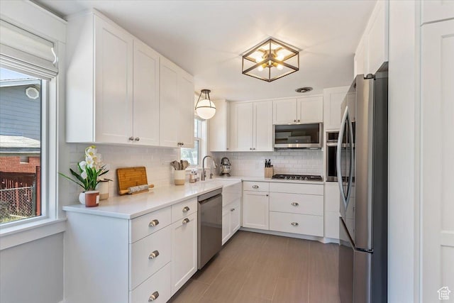 1393 E Davis Ave, Logan, UT 84321 - kitchen with appliances with stainless steel finishes, backsplash, white cabinets, light countertops, and a chandelier