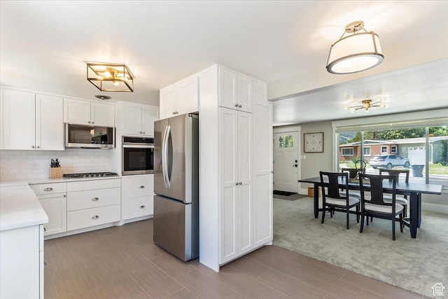 1393 E Davis Ave, Logan, UT 84321 - kitchen with appliances with stainless steel finishes, light countertops, decorative backsplash, white cabinetry, and light carpet