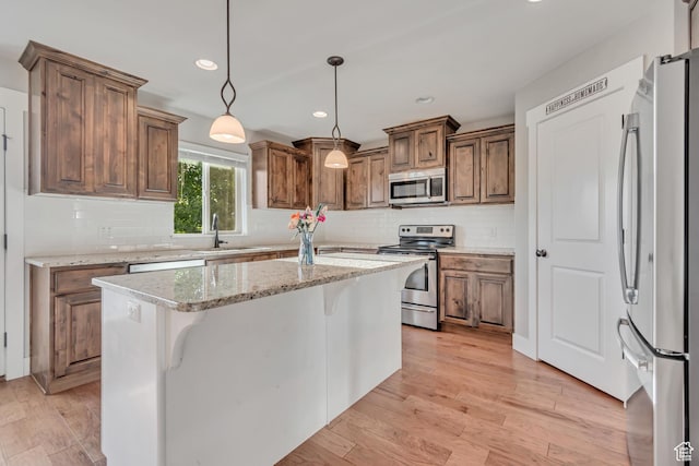 1602 S 790 W, Payson, UT 84651 - kitchen with appliances with stainless steel finishes, decorative backsplash, a kitchen island, pendant lighting, and brown cabinets