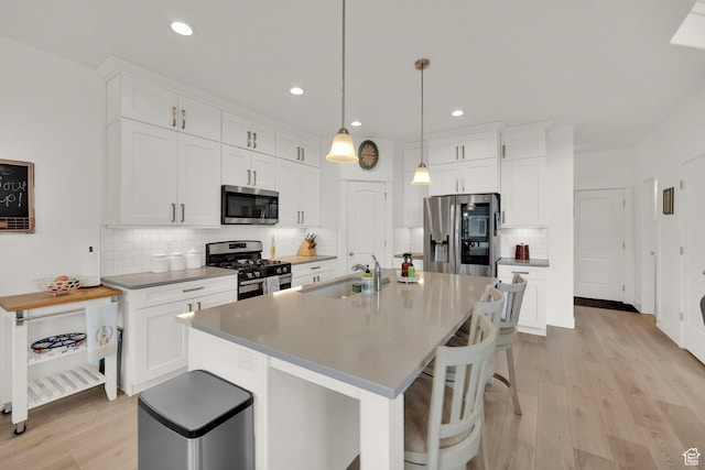 4655 N Ibapah St, Eagle Mountain, UT 84005 - kitchen featuring stainless steel appliances, tasteful backsplash, a breakfast bar area, white cabinetry, and light wood-style floors