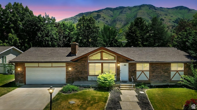 1520 N 1600 E, North Logan, UT 84341 - view of front facade with concrete driveway, a mountain view, an attached garage, a chimney, and stone siding