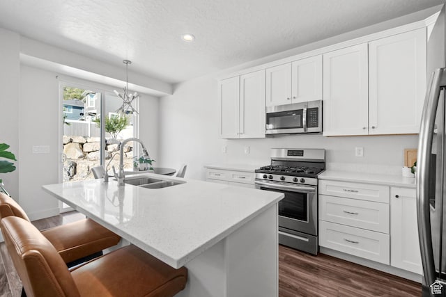 3712 E Long Ridge Dr Unit 124, Eagle Mountain, UT 84005 - kitchen with stainless steel appliances, dark wood-style flooring, white cabinets, a textured ceiling, and a kitchen island with sink