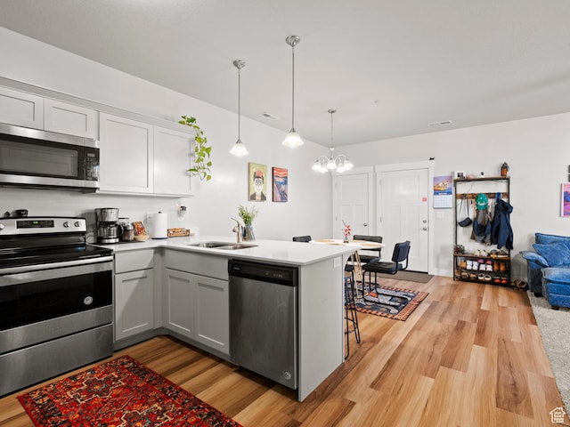 3795 W 2280 N Unit A201, Lehi, UT 84043 - kitchen featuring stainless steel appliances, light wood finished floors, a chandelier, a peninsula, and light countertops