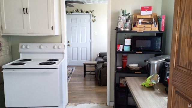 131 6th W, East Carbon, UT 84520 - kitchen with white range with electric cooktop, black microwave, white cabinetry, light wood-style flooring, and a ceiling fan