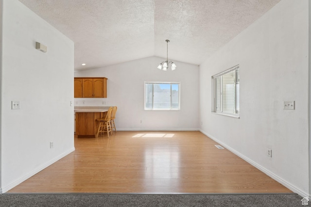 827 S 1030 W, Richfield, UT 84701 - unfurnished living room with light wood-type flooring, vaulted ceiling, a chandelier, and a textured ceiling