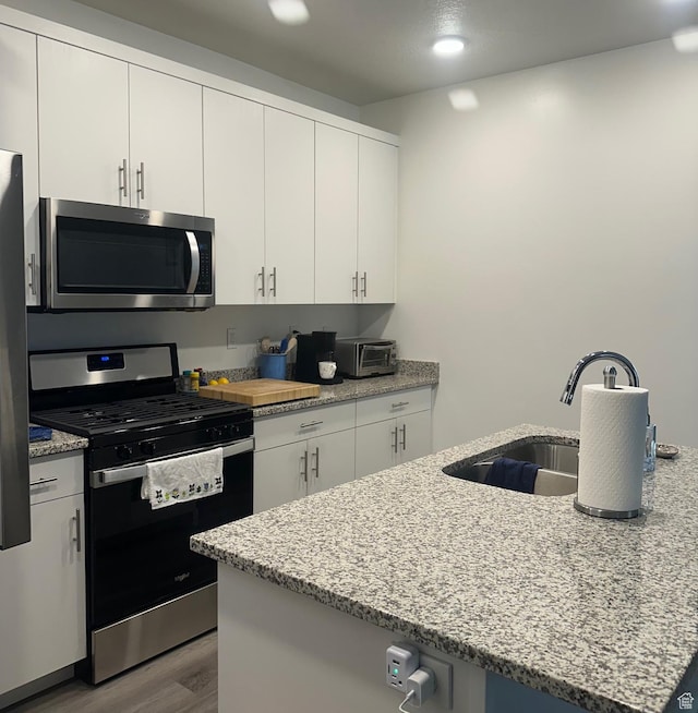 470 W 15 S Unit F201, Providence, UT 84332 - kitchen featuring appliances with stainless steel finishes, wood finished floors, light stone counters, white cabinets, and recessed lighting