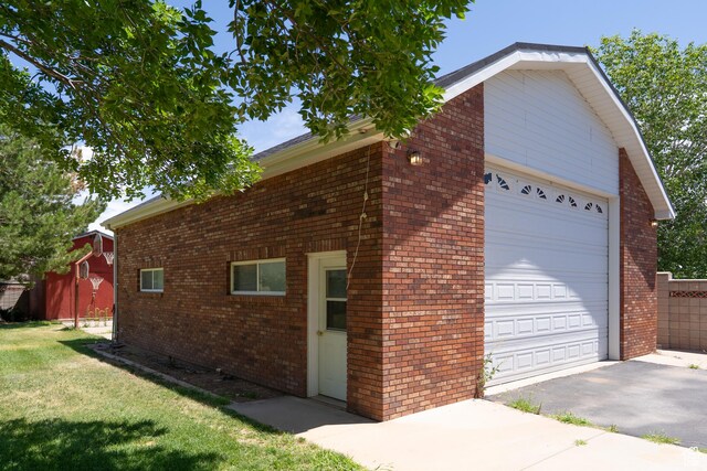 4163 S Beeman Rd, Moab, UT 84532 - view of side of property featuring a garage, brick siding, a yard, and an outbuilding
