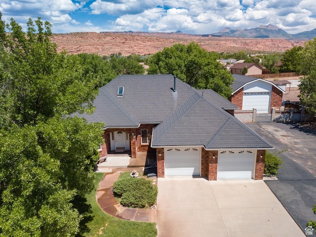 4163 S Beeman Rd, Moab, UT 84532 - view of front facade featuring brick siding, concrete driveway, a garage, and a mountain view