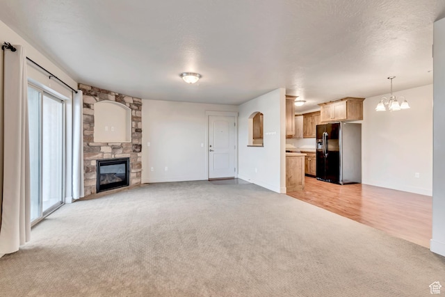 1045 S 1700 W Unit 1213, Payson, UT 84651 - unfurnished living room featuring light colored carpet, a stone fireplace, and a chandelier