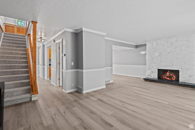 1870 E Monterey Dr, Salt Lake City, UT 84121 - unfurnished living room featuring crown molding, wood finished floors, a stone fireplace, stairway, and a textured ceiling