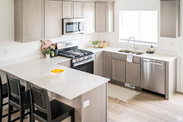 425 W Domain Ln, Grantsville, UT 84029 - kitchen featuring stainless steel appliances, a peninsula, light wood-style flooring, a breakfast bar, and light countertops
