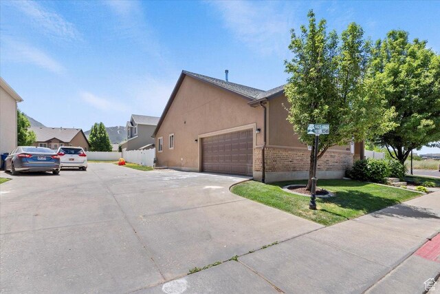 1025 N Apple Seed Ln, Santaquin, UT 84655 - view of side of home with stucco siding, an attached garage, concrete driveway, and a residential view