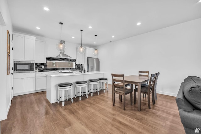 5930 Cardiff Pass Rd, Mountain Green, UT 84050 - kitchen featuring stainless steel refrigerator with ice dispenser, built in microwave, white cabinetry, a kitchen bar, and light wood-style flooring