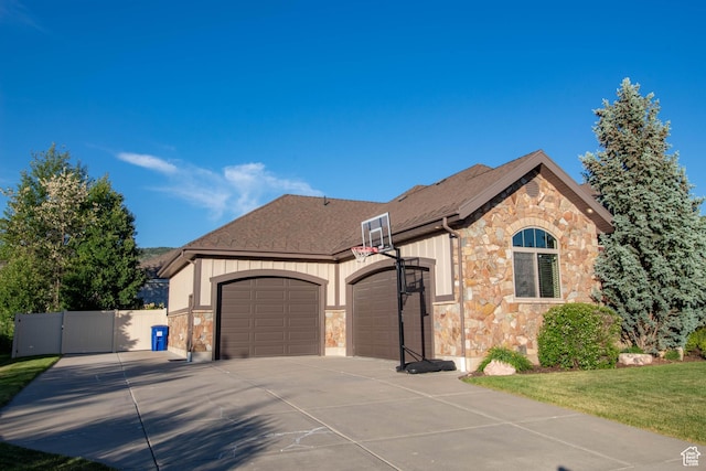 5818 N Cambridge Dr E, Mountain Green, UT 84050 - view of front facade with stone siding, an attached garage, concrete driveway, a gate, and a shingled roof