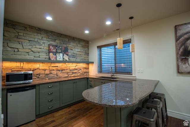 5818 N Cambridge Dr E, Mountain Green, UT 84050 - kitchen featuring stainless steel microwave, refrigerator, a peninsula, dark wood-style floors, and a kitchen breakfast bar