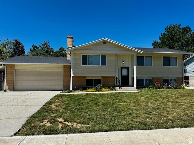 7026 S Wood Green Rd, West Jordan, UT 84084 - split foyer home with an attached garage, brick siding, a chimney, concrete driveway, and a front lawn