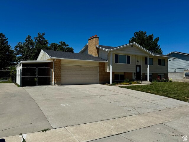 7026 S Wood Green Rd, West Jordan, UT 84084 - bi-level home featuring brick siding, an attached garage, driveway, a chimney, and a front yard