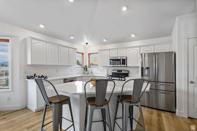 4212 N Majors St E, Eagle Mountain, UT 84005 - kitchen with stainless steel appliances, a kitchen bar, white cabinetry, light wood-type flooring, and recessed lighting