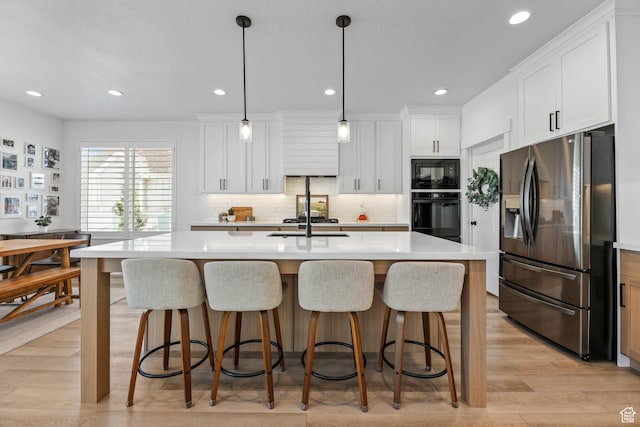 10243 S Dial Ct, South Jordan, UT 84009 - kitchen with black appliances, light countertops, a breakfast bar area, and recessed lighting