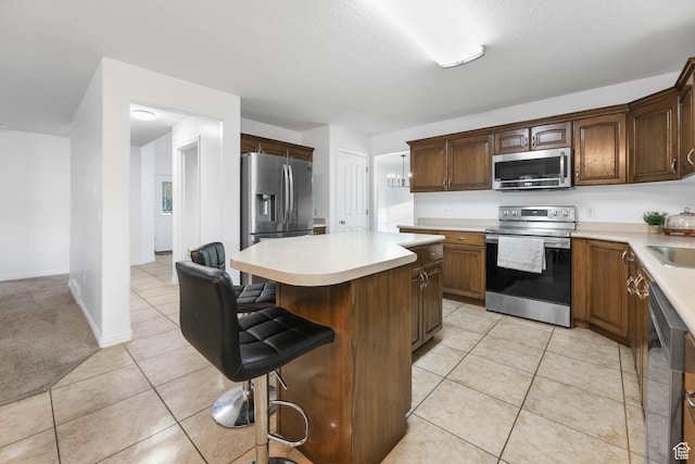 10314 S 3970 W, South Jordan, UT 84009 - kitchen featuring appliances with stainless steel finishes, a kitchen island, a kitchen breakfast bar, light countertops, and light tile patterned flooring