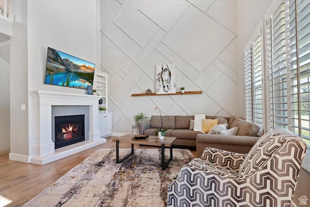 12140 S Galena Grove Way W, Draper, UT 84020 - living area featuring wood finished floors, a fireplace, built in shelves, a decorative wall, and a high ceiling
