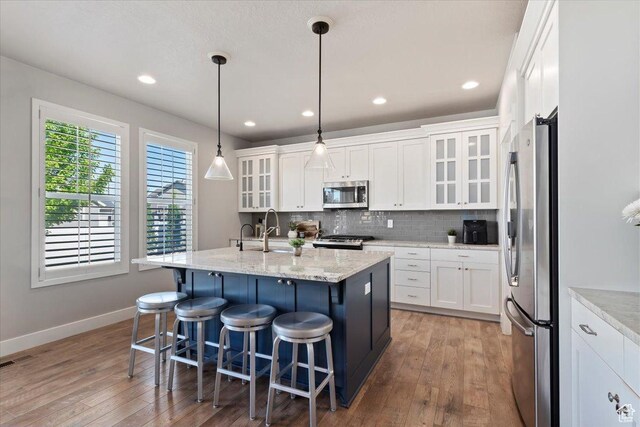 12140 S Galena Grove Way W, Draper, UT 84020 - kitchen with appliances with stainless steel finishes, wood-type flooring, decorative backsplash, white cabinetry, and recessed lighting