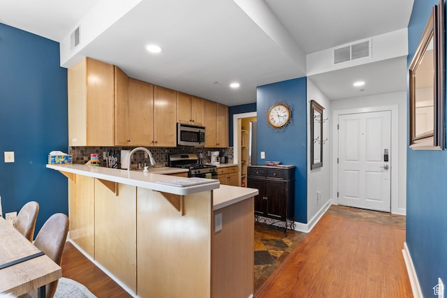 6785 N 2200 W Unit 207, Park City, UT 84098 - kitchen with stainless steel appliances, a breakfast bar area, backsplash, a peninsula, and light countertops