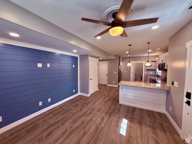 12887 S Wild Mare Way, Riverton, UT 84096 - kitchen featuring ceiling fan, white cabinetry, a peninsula, dark wood finished floors, and light stone counters