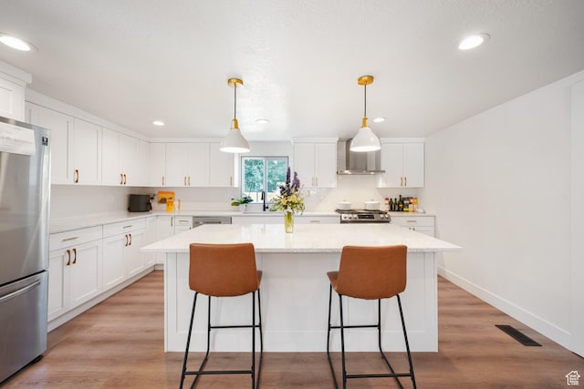 2500 E Simpson Ave S, Salt Lake City, UT 84109 - kitchen with stainless steel appliances, wall chimney range hood, a center island, a kitchen breakfast bar, and white cabinetry