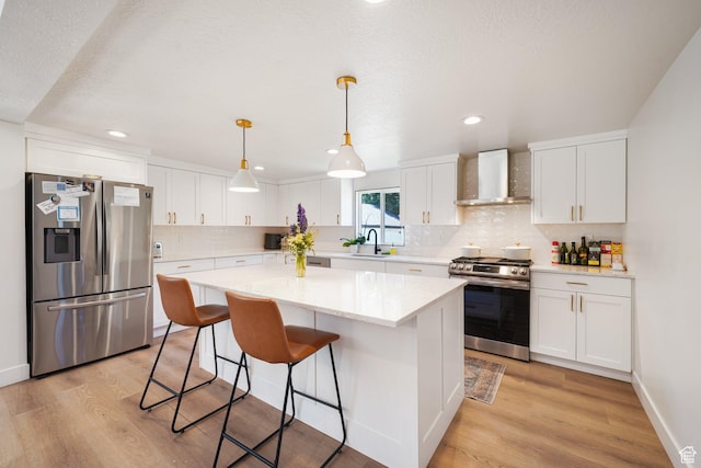 2500 E Simpson Ave S, Salt Lake City, UT 84109 - kitchen featuring appliances with stainless steel finishes, wall chimney range hood, light wood-style floors, a kitchen bar, and recessed lighting