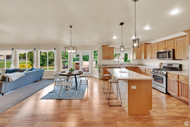 356 Warley Way, Stansbury Park, UT 84074 - kitchen with appliances with stainless steel finishes, open floor plan, light countertops, a kitchen island, and a breakfast bar