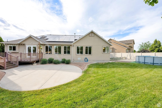 356 Warley Way, Stansbury Park, UT 84074 - rear view of house featuring a wooden deck, roof mounted solar panels, a fenced backyard, and stucco siding