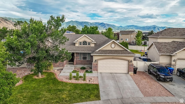 356 Warley Way, Stansbury Park, UT 84074 - view of front of house featuring roof with shingles, an attached garage, brick siding, a mountain view, and driveway