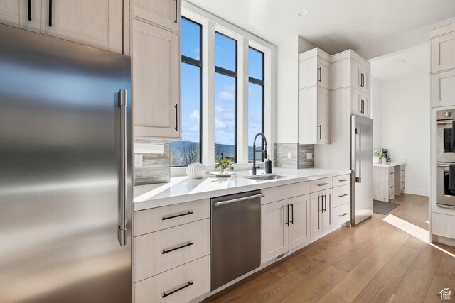 8960 Parleys Ln, Park City, UT 84098 - kitchen featuring stainless steel appliances, decorative backsplash, light wood-type flooring, light countertops, and white cabinetry