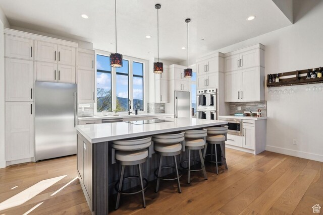 8960 Parleys Ln, Park City, UT 84098 - kitchen with stainless steel appliances, backsplash, light countertops, light wood finished floors, and white cabinetry