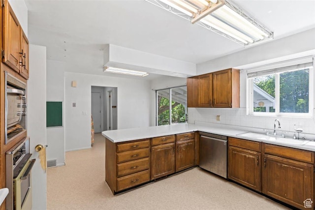 220 S Coleman St W, Tooele, UT 84074 - kitchen featuring stainless steel appliances, a peninsula, decorative backsplash, light countertops, and brown cabinets