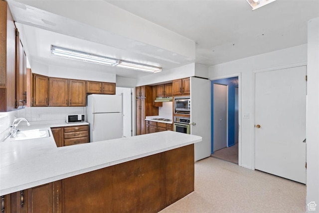 220 S Coleman St W, Tooele, UT 84074 - kitchen with appliances with stainless steel finishes, light countertops, under cabinet range hood, a peninsula, and brown cabinetry