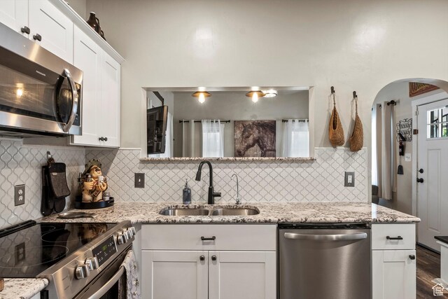 3530 Madison Ave, Ogden, UT 84403 - kitchen with appliances with stainless steel finishes, arched walkways, white cabinetry, and backsplash