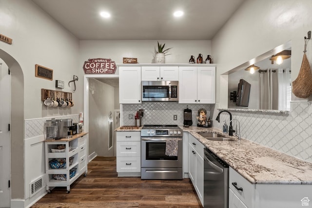 3530 Madison Ave, Ogden, UT 84403 - kitchen with appliances with stainless steel finishes, decorative backsplash, arched walkways, white cabinetry, and light stone countertops