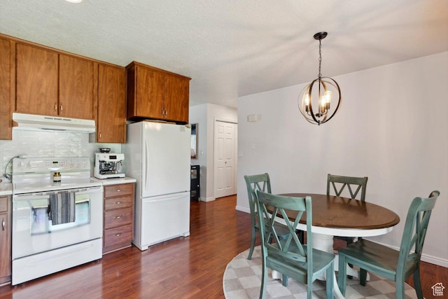 435 E 2100 N, North Ogden, UT 84414 - kitchen featuring white appliances, under cabinet range hood, brown cabinetry, a chandelier, and dark wood-style flooring