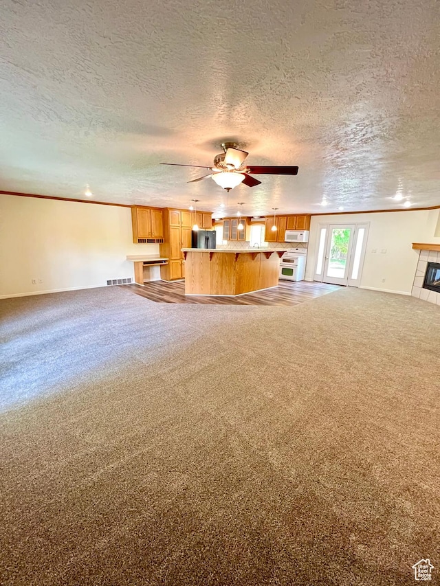 90 W 640 N, Richfield, UT 84701 - unfurnished living room with carpet, ceiling fan, a textured ceiling, crown molding, and a tiled fireplace