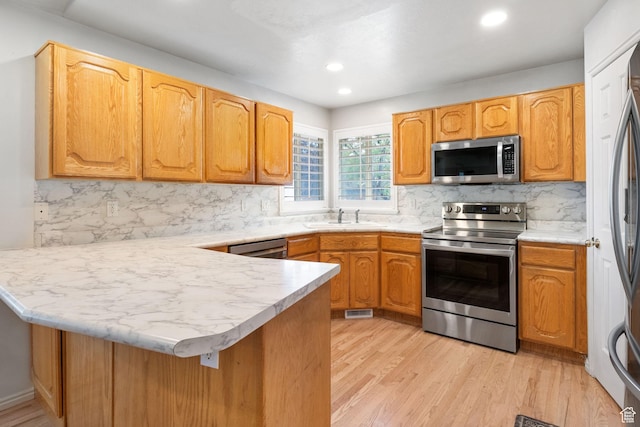 9353 S 4460 W, West Jordan, UT 84088 - kitchen featuring appliances with stainless steel finishes, a peninsula, decorative backsplash, light wood-style floors, and recessed lighting