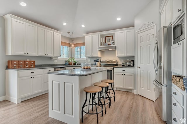 5718 W Silver Rose Cir S, Herriman, UT 84096 - kitchen with stainless steel appliances, white cabinetry, a kitchen island, light wood-style floors, and a kitchen bar