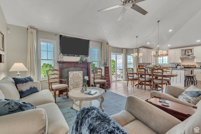 5718 W Silver Rose Cir S, Herriman, UT 84096 - living area with a fireplace, light wood-style flooring, a chandelier, lofted ceiling, and recessed lighting