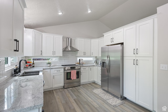 10787 S Pine Shadow Rd, South Jordan, UT 84009 - kitchen featuring stainless steel appliances, wall chimney exhaust hood, vaulted ceiling, decorative backsplash, and light wood-type flooring